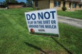 an EPA sign outdoors: "DO NOT play in the dirt or around the mulch"