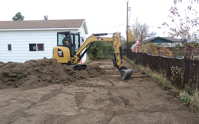 Image of construction vehicle cleaning up residential yard