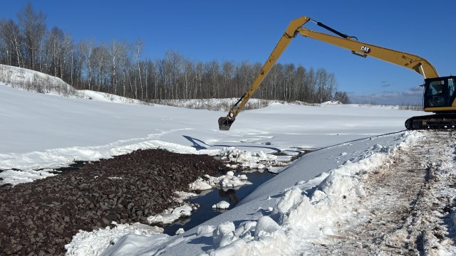 large machine placing rock on slop of Wire Mill Pond