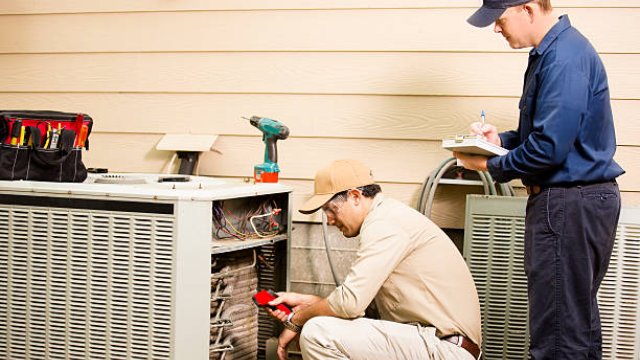 Two technicians servicing an outdoor AC unit