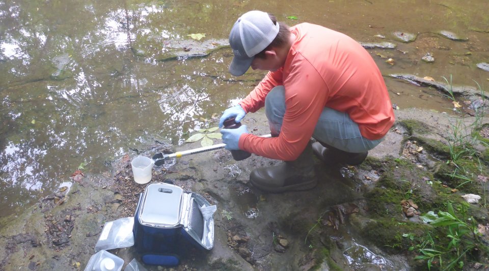 A crew member collects a water sample.