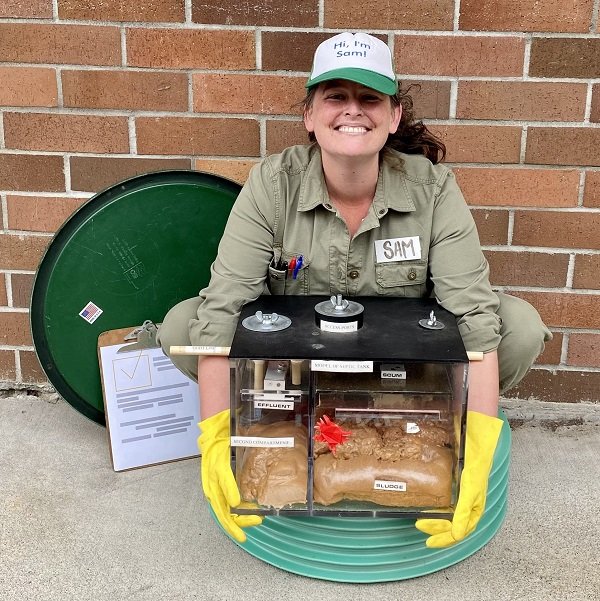 Photo of person demonstrating how septic systems work with a model of a septic system