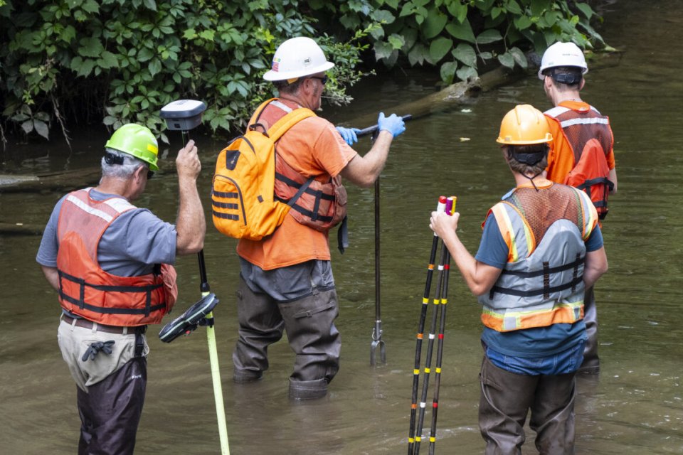 Four people inside Leslie Run collecting sediment samples