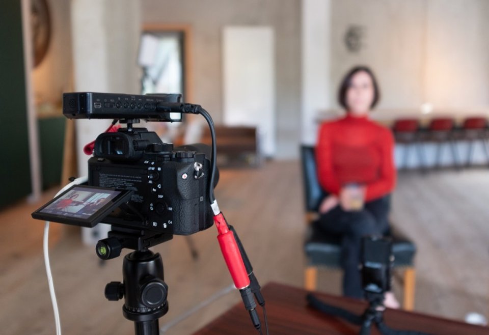 Woman sitting in a chair in front of a camera on a tripod