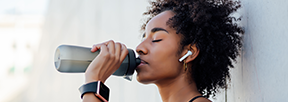 A women drinking water from a sports water bottle.