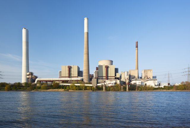 Factory building with smoke stacks above water body