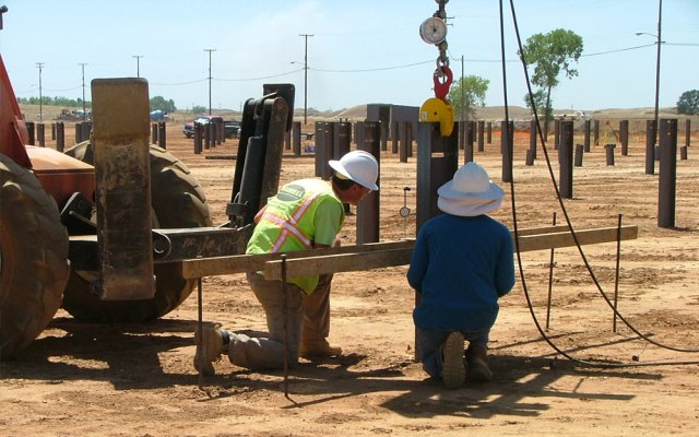 Photo of construction workers adding the foundations of a solar farm