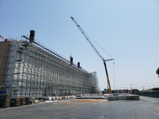 Stack Removal Preparation: building exterior with scaffolding and crane with cable conecting to stack on roof. Click to Enlarge