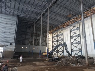 Interior of Segment 3 building with worker in protective gear, construction equipment and debris.