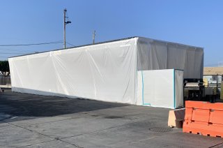 Exterior photograph of one of two haz-waste storage structures covered in white plastic.