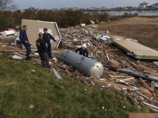 EPA responders at a disaster scene, with an overturned propane tank and wood debris