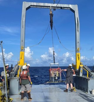 Deploying the SPI-PV camera system: back of ship with crane moving the camera system into the water