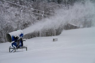 A snow machine making snow along a snowy ski run