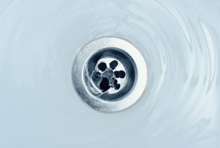 closeup of metal drain against white ceramic