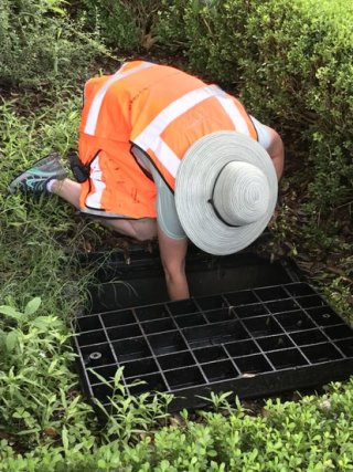 Worker reaching in drain.
