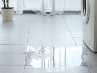 Water leaking onto the floor from a clothes washer machine.
