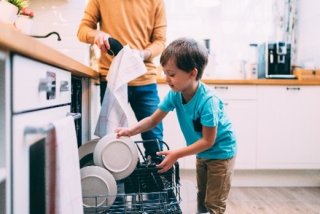 a child loading a dishwasher