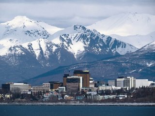 The city of Anchorage Alaska as viewed from the water with snowy mountains in the background. 