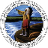 This is a logo of a native american man with a feathered headdress holding a blanket and standing at the shore of a river